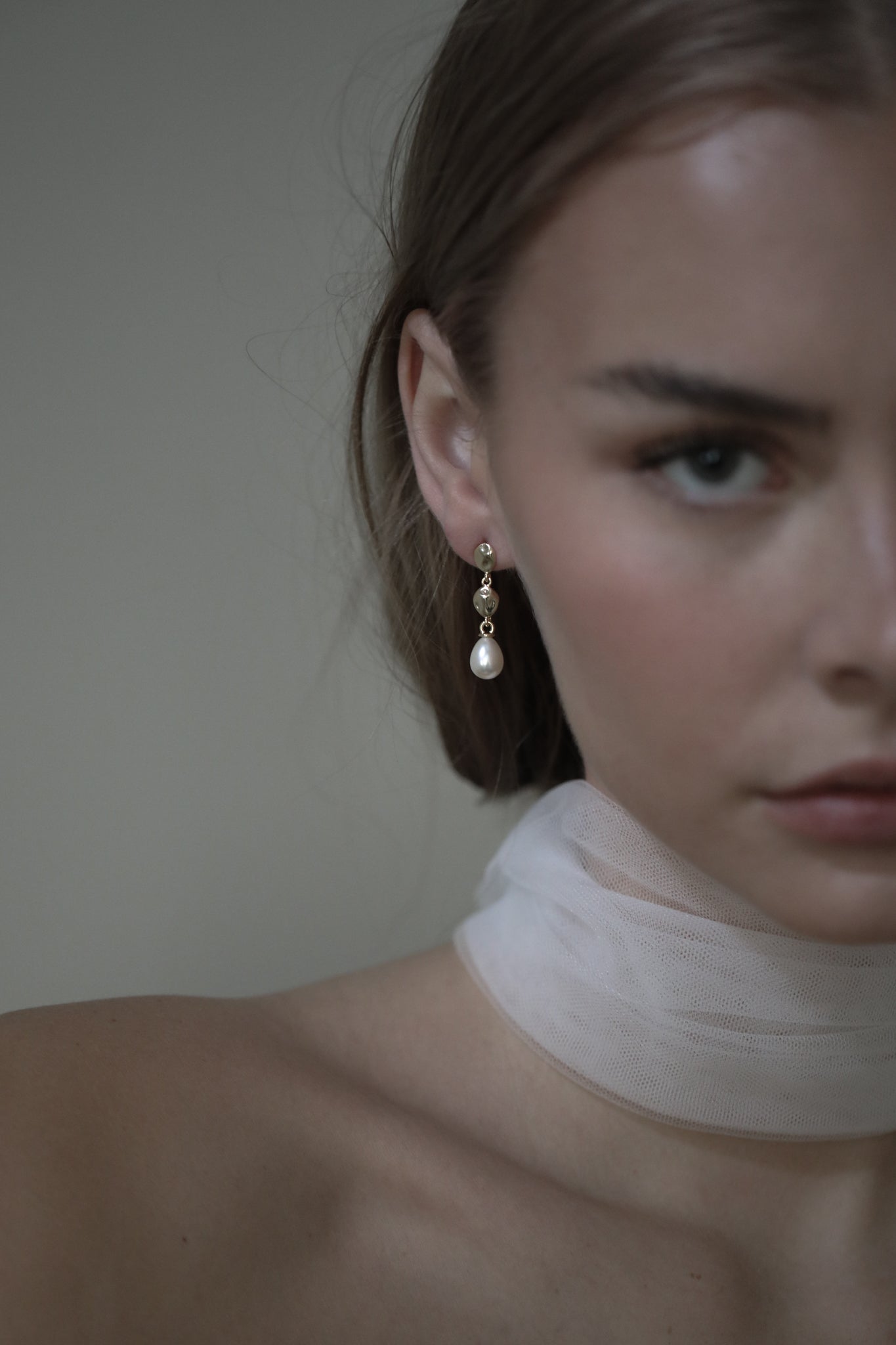 Bride wearing silk bridal scarf in a strapless wedding gown paired with a sculptural gold pearl drop earring