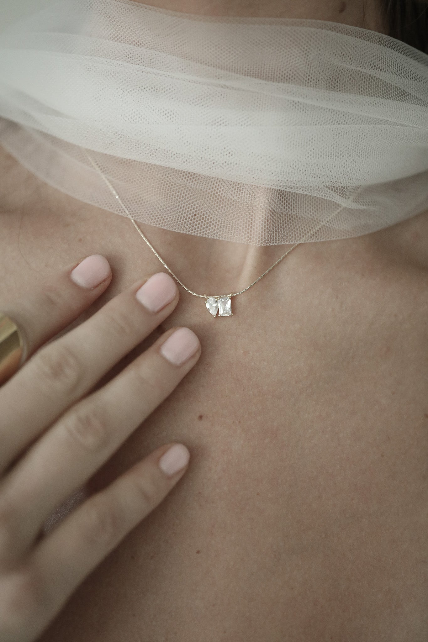 Close-up of a CZ Pendant necklace by Studio Bride on bride with tulle scarf
