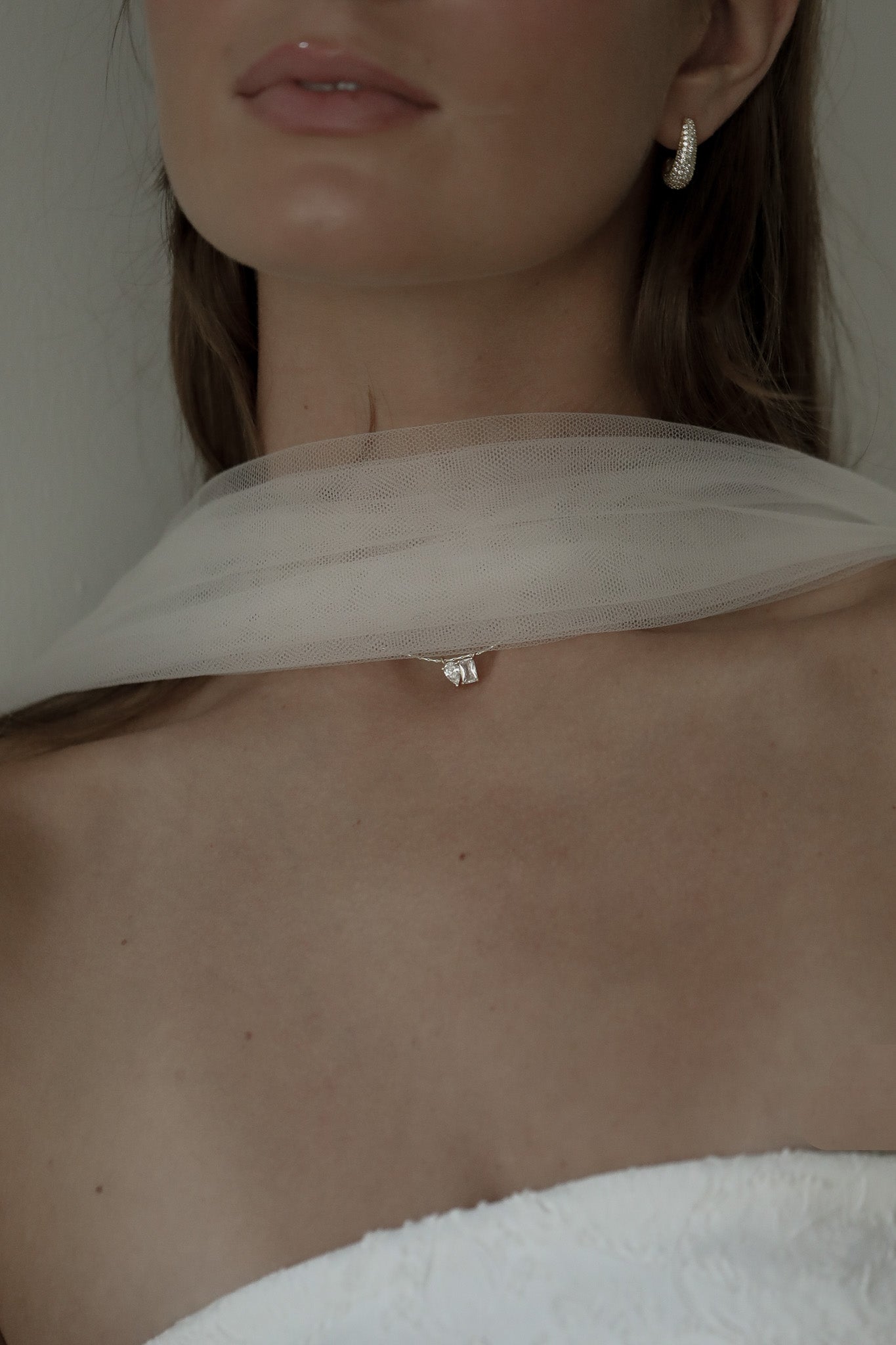 Bride wearing the baguette and teardrop CZ necklace by Studio Bride paired with a tulle scarf