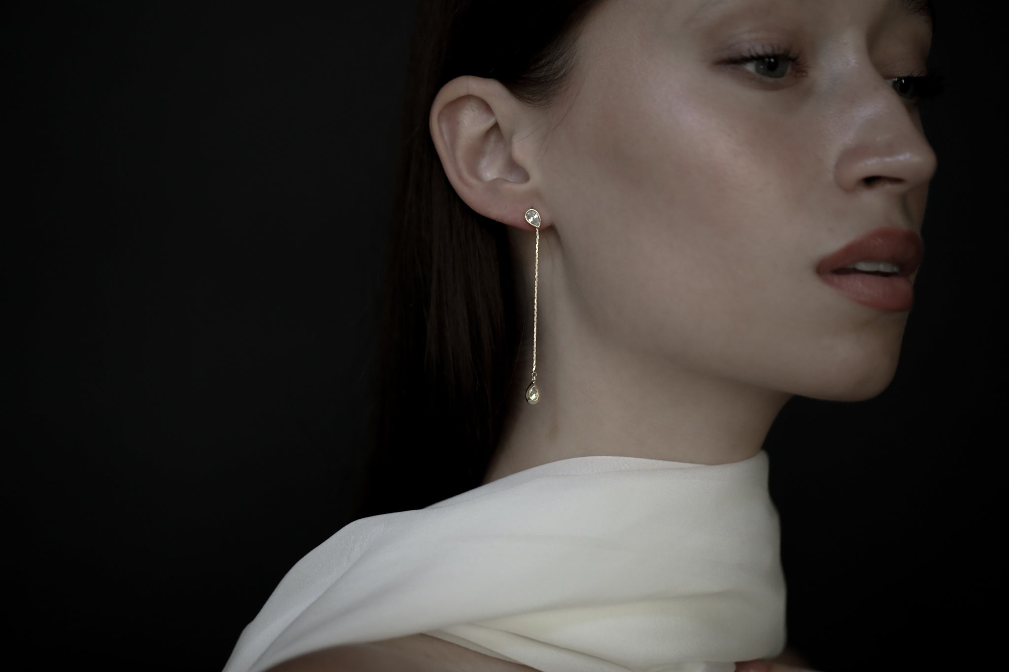 Gold strand earring with bezeled crystal accents worn by brunette bride with bridal scarf