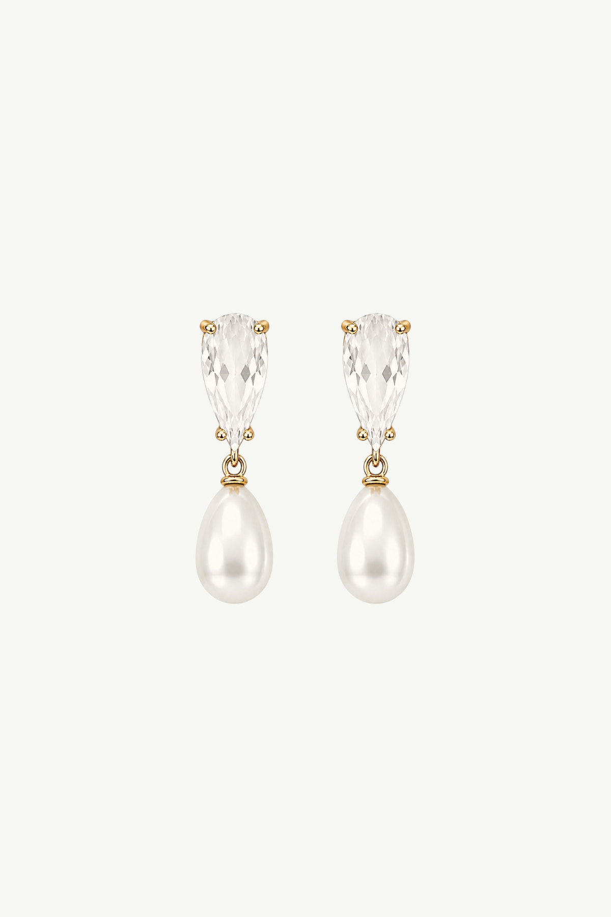 A pair of gold drop earrings featuring pear-cut clear crystals above teardrop-shaped white pearls, set against a solid off-white background.