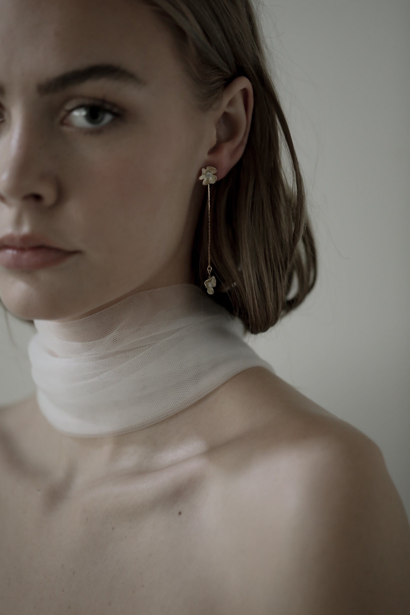 Gold plated floral strand earring with rhinestone accents worn by brunette bride wearing a silk bridal scarf