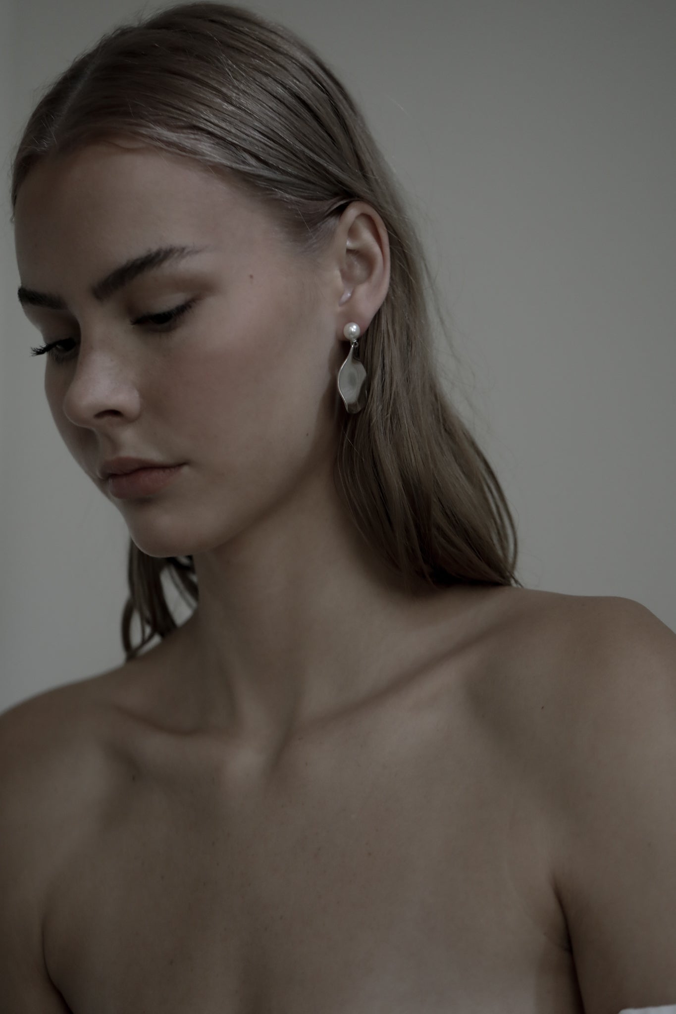 Brunette bride wearing strapless bridal gown and sculptural irregular gold drop earrings with a pearl stud accent