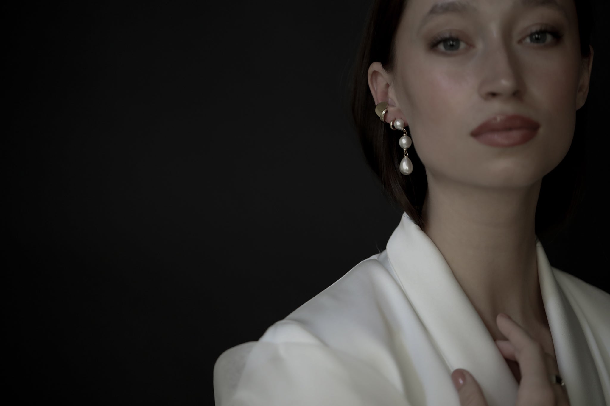 Bride wearing wedding suit with stacked gold and pearl earrings