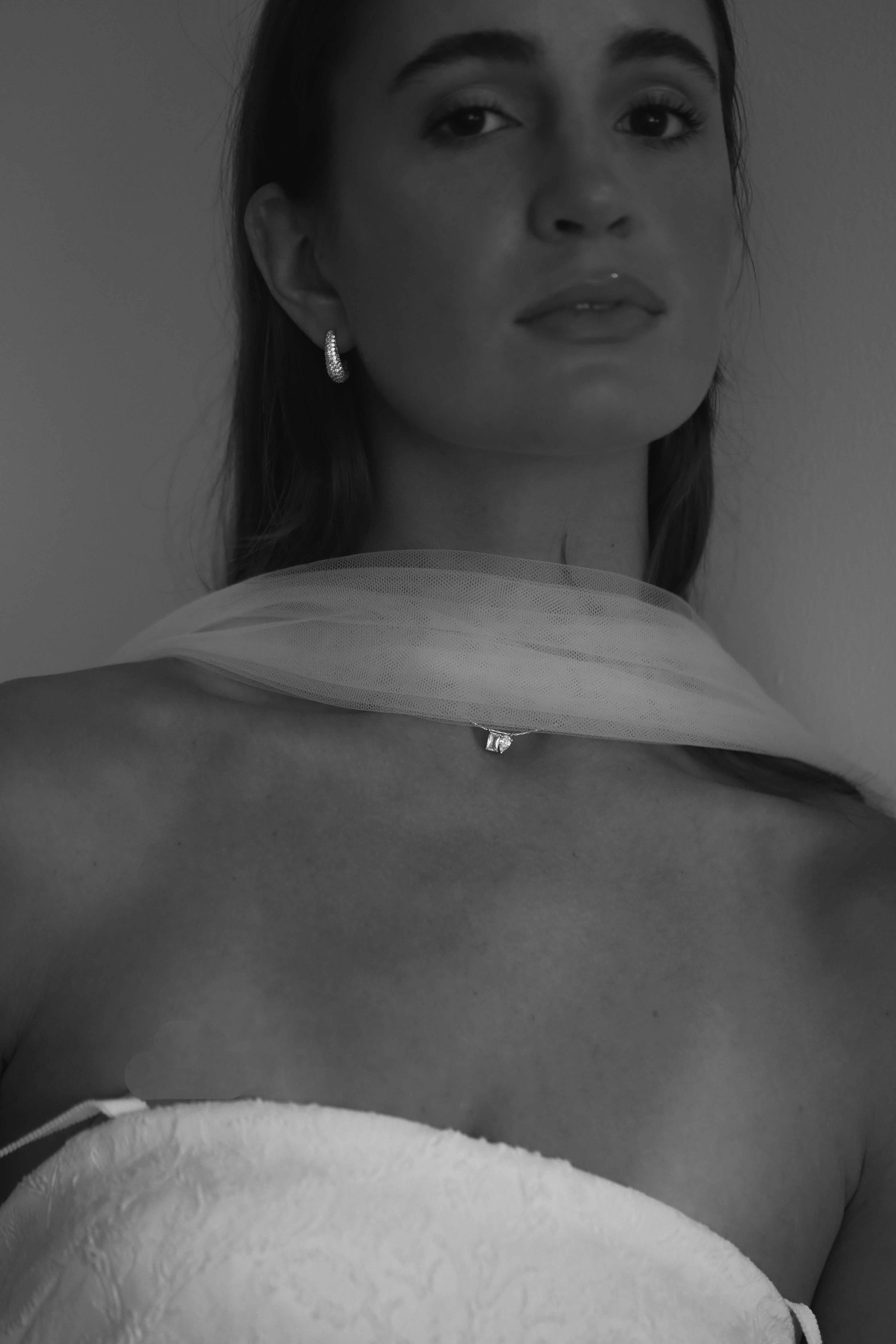 Black and white close-up of a bride wearing silk scarf and gold pendant necklace by Studio Bride