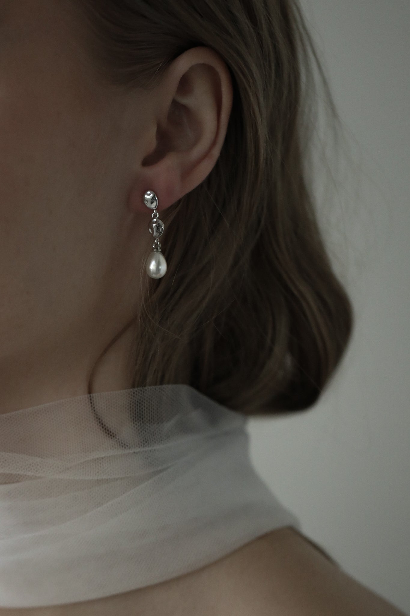 Close up of bride wearing the silver gilded tier drop earring with bridal pearl drop earring accent paired with a silk necktie